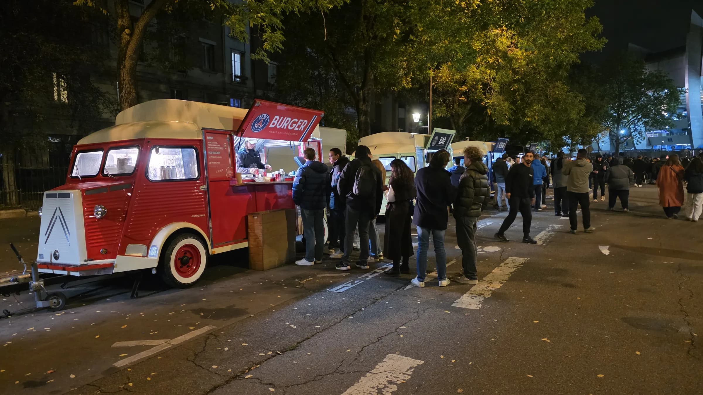 File de supporters devant le Citroën HY Burger rouge du PSG le long du Parc des Princes